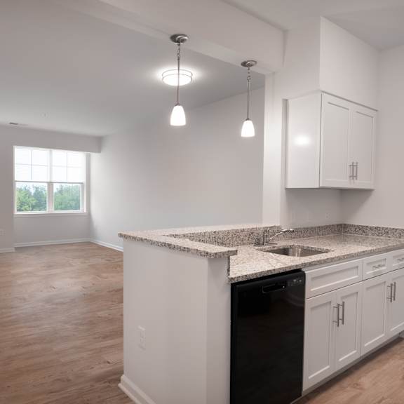 an empty kitchen and living room with white cabinets and granite counter tops