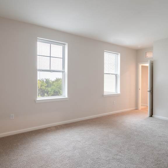 an empty living room with two windows and a door