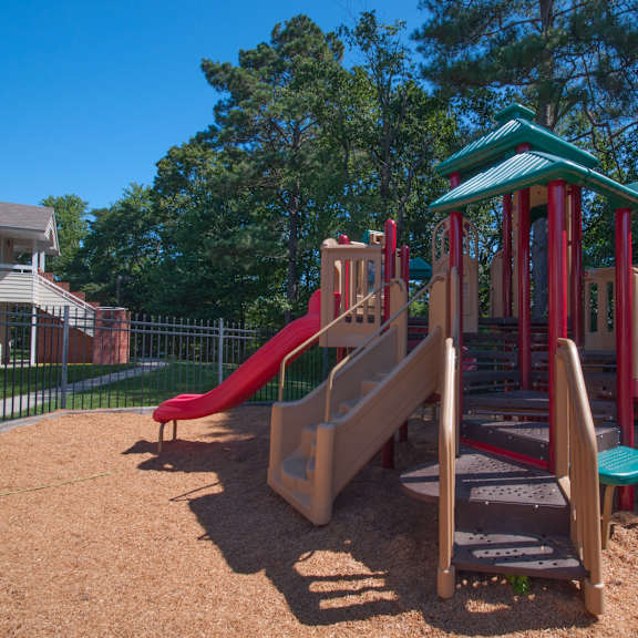 a playground with a red slide and a green roofed structure.