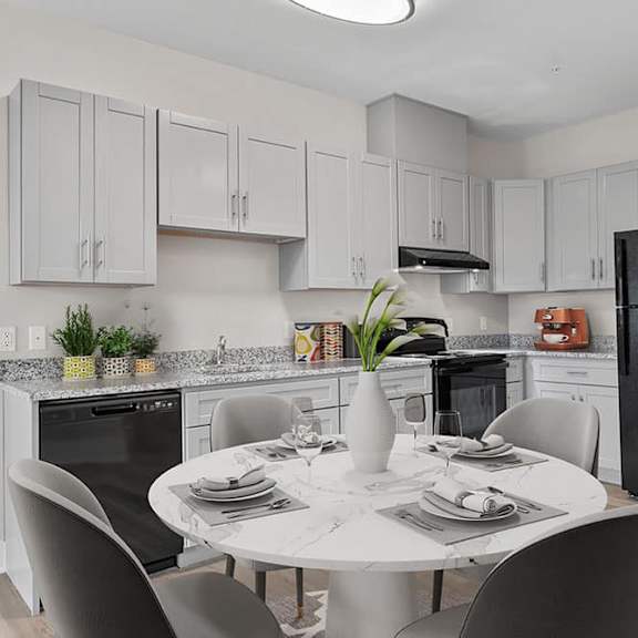 a kitchen with a table set for two and a black refrigerator.
