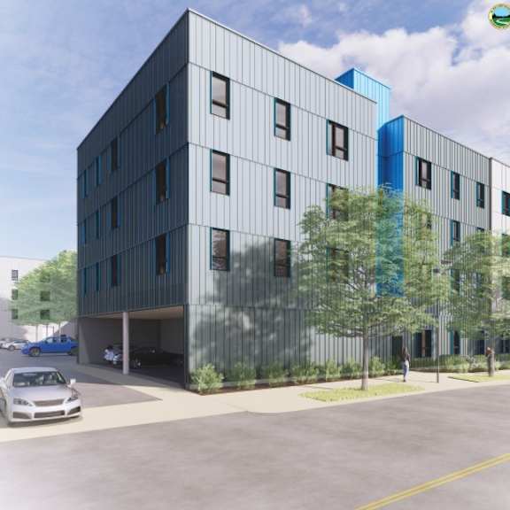 a modern building with a glass facade and a parking lot in front.