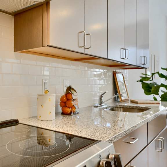 now leasing senior 1-bedrooms in baltimore, md. a white kettle is on a black stove in a kitchen.