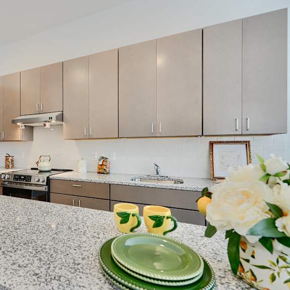 now leasing senior 1-bedrooms in baltimore, md. a kitchen with a granite countertop and a refrigerator.