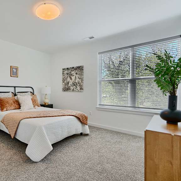 now leasing senior 1-bedrooms in baltimore, md. a bedroom with a bed, chair, and window.