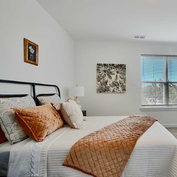 now leasing senior 1-bedrooms in baltimore, md. a bedroom with a bed, dresser, and window.