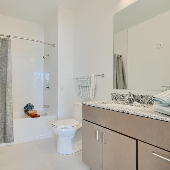 now leasing senior 1-bedrooms in baltimore, md. a white toilet sits in a bathroom with a white shower curtain.