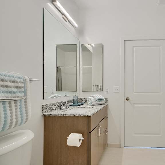 now leasing senior 1-bedrooms in baltimore, md. a bathroom with a sink, mirror, and towel rack.