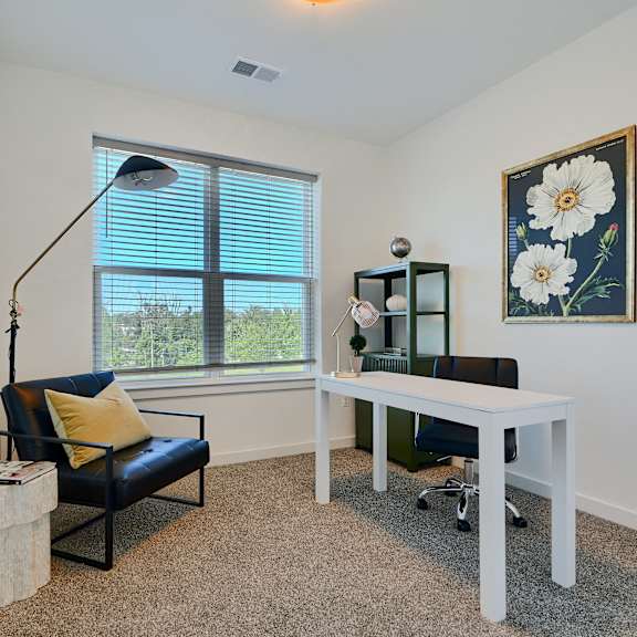 now leasing senior 1-bedrooms in baltimore, md. a room with a black chair, a white desk, and a painting of flowers on the wall.