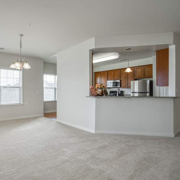 an empty living room with a kitchen in the corner
