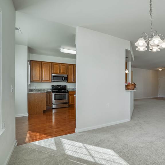 an empty living room and kitchen with wood flooring and white walls
