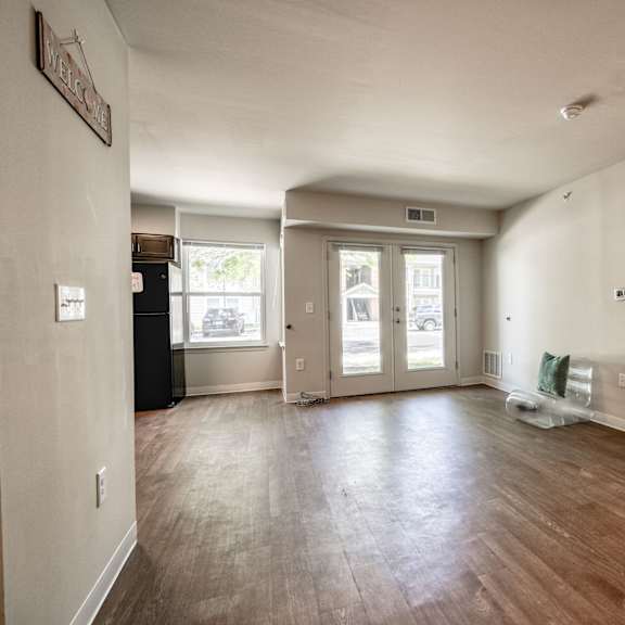 the living room and dining room of an empty home with wood floors and white walls