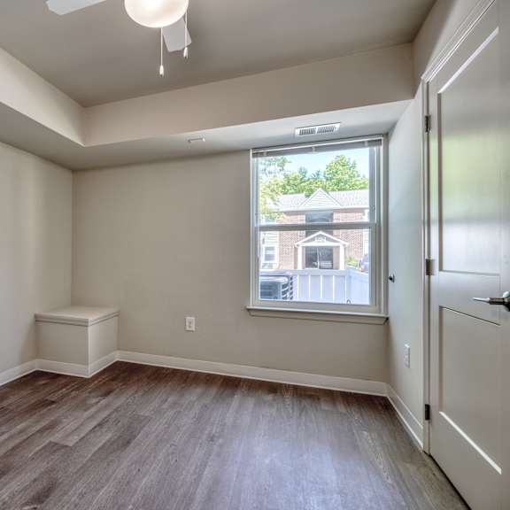 an empty living room with wood flooring and a window