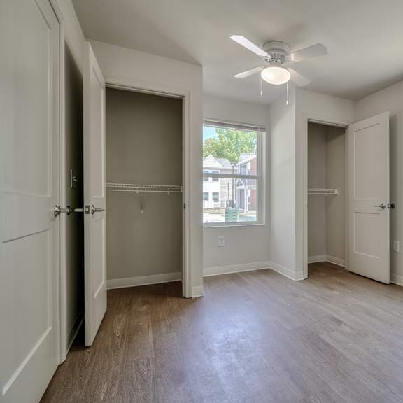 an empty living room with wood floors and a ceiling fan