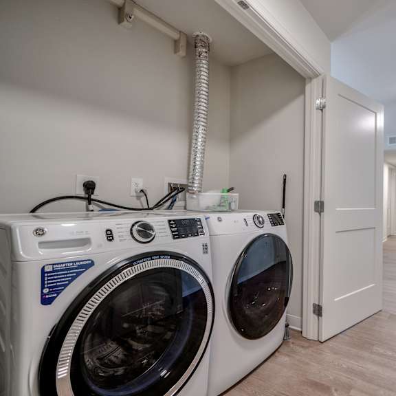 a laundry room with a washer and dryer and a hallway with a door