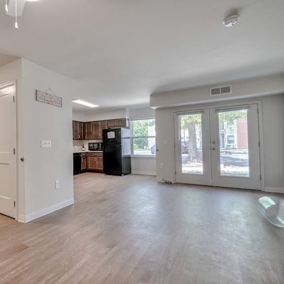 an empty living room and kitchen with white walls and wood floors