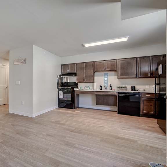 an empty living room and kitchen with wood flooring and black appliances