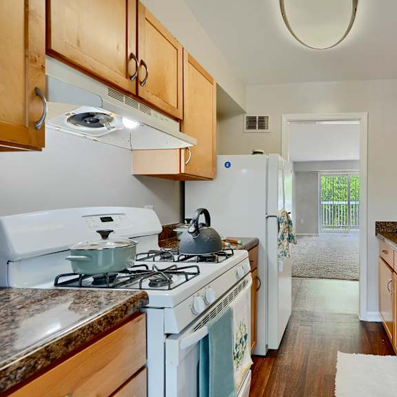 a kitchen with a white stove top oven and wooden cabinets.