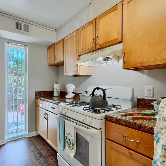 a kitchen with a white stove top oven and wooden cabinets.