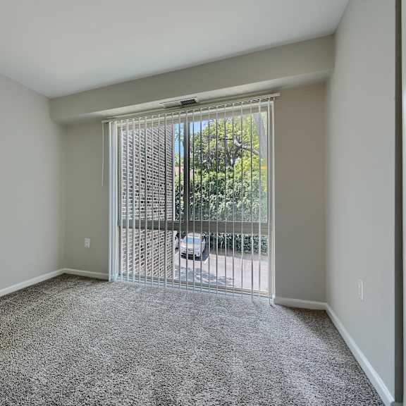 a room with a carpeted floor and a sliding glass door leading to a balcony.