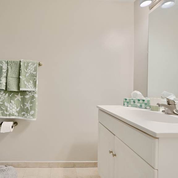 a bathroom with a white sink and a green and white towel hanging on the wall.