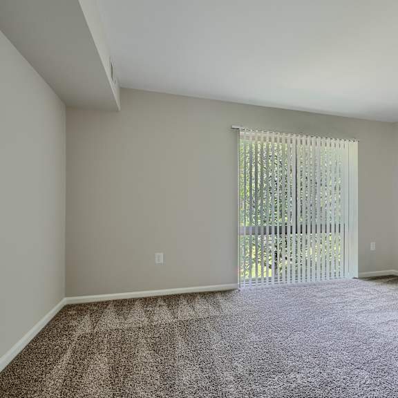 a room with a carpeted floor and a sliding glass door leading to a balcony.