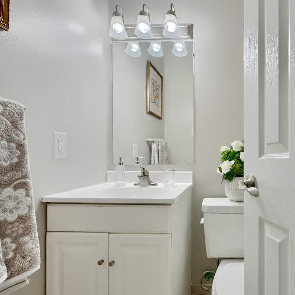 a white bathroom with a sink, mirror, and toilet.