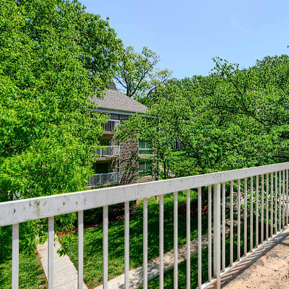 a white railing overlooks a lush green yard.