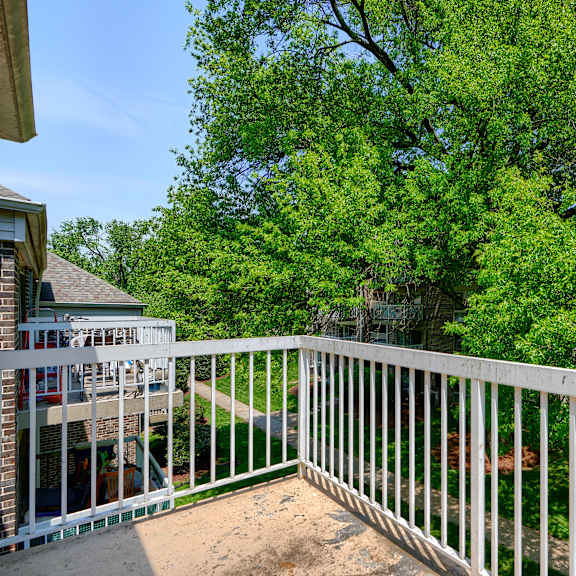 a white railing overlooks a yard with a tree.