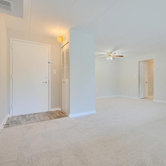 a spacious room with a ceiling fan and two doors.