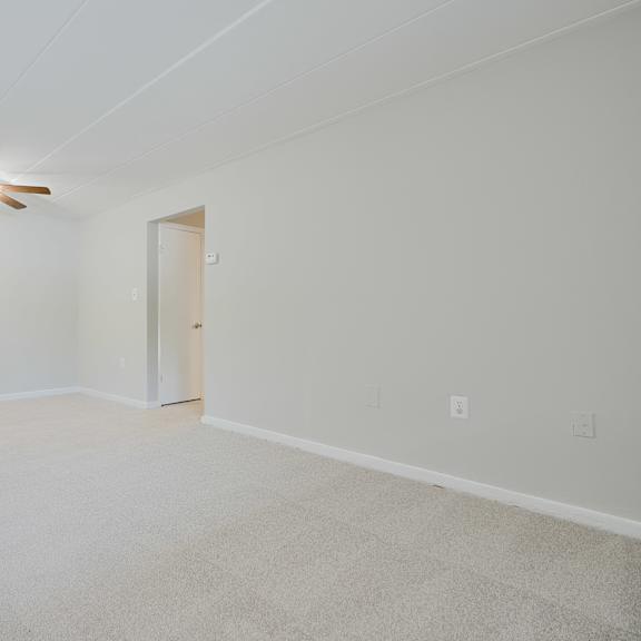 a room with a ceiling fan and carpeted floor.