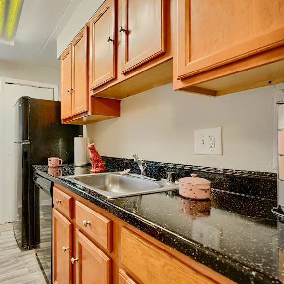 a kitchen with black countertops and wooden cabinets.