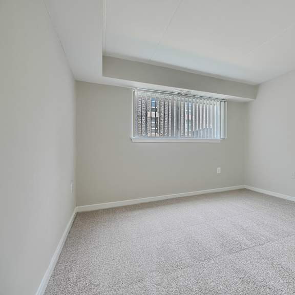 a room with a carpeted floor and a window with blinds.