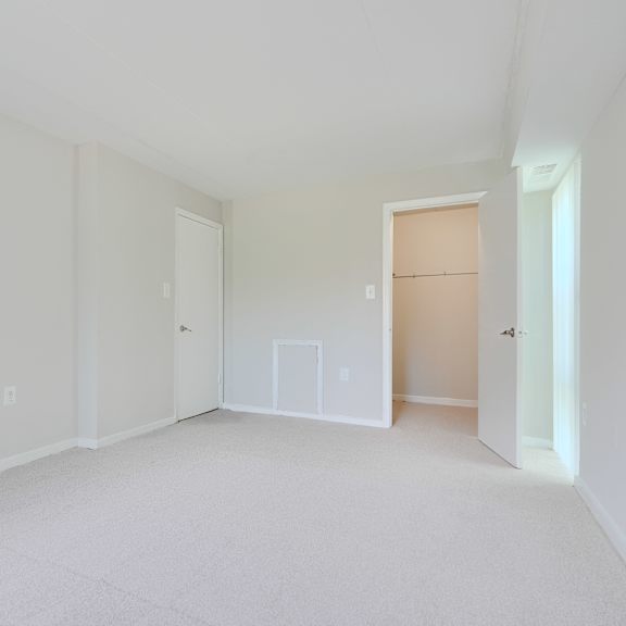 a white room with a carpeted floor and three doors.