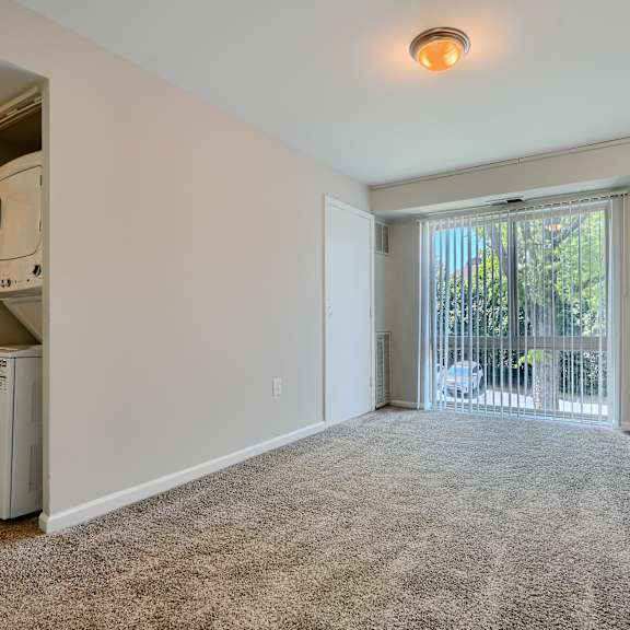 a spacious room with a carpeted floor and a window with blinds.