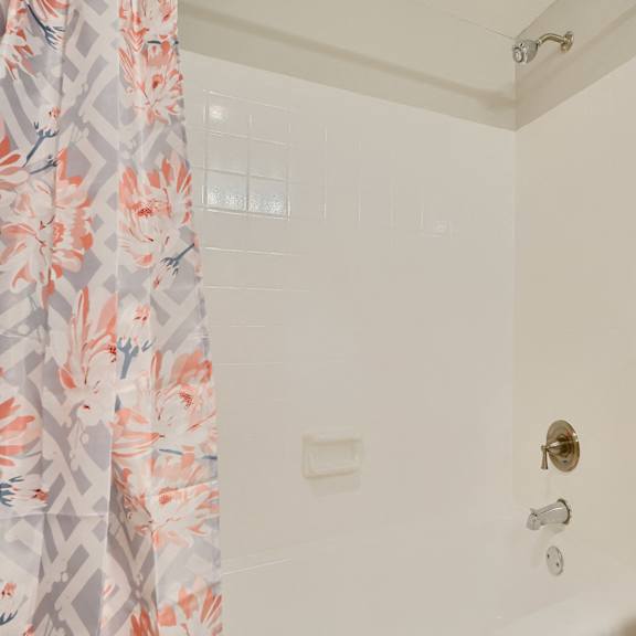 a white bathroom with a floral shower curtain.
