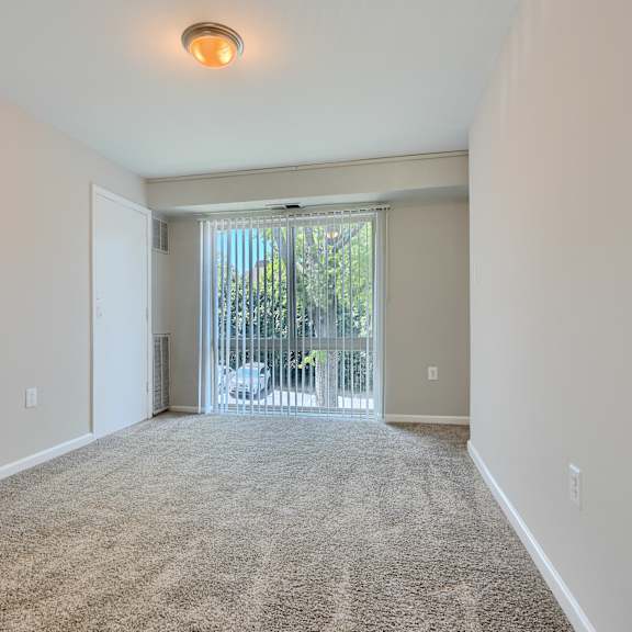 a room with a carpeted floor and a sliding glass door leading to a balcony.