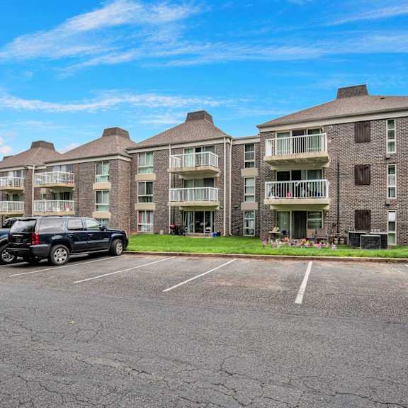 a parking lot in front of an apartment building with two cars parked in front