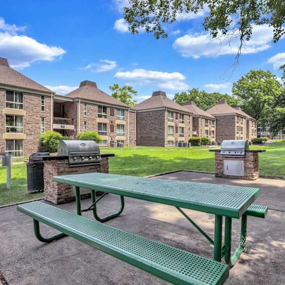 a green picnic table in front of an apartment building with barbecue pits