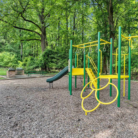 a yellow swing set in a park with trees