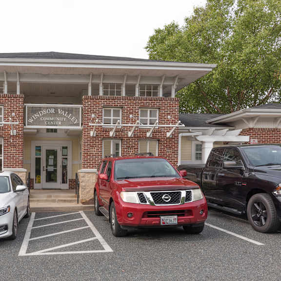 a white car is parked in front of a brick building.