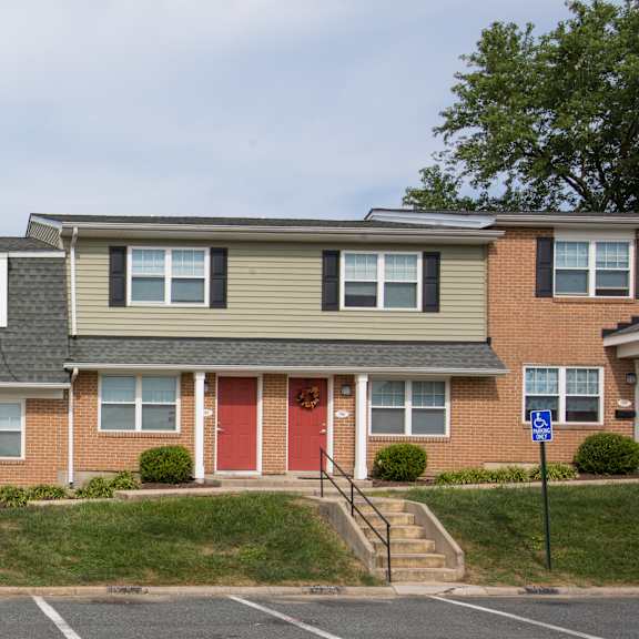 a row of townhouses with red doors and green bushes.