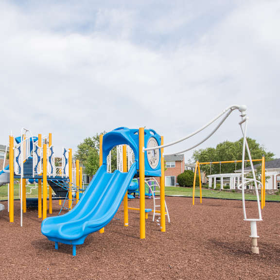 a playground with a blue slide and yellow poles.