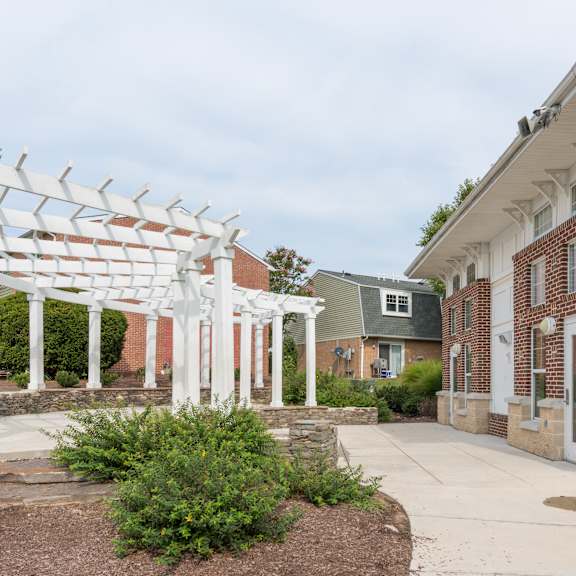 a white pergola is in front of a building.