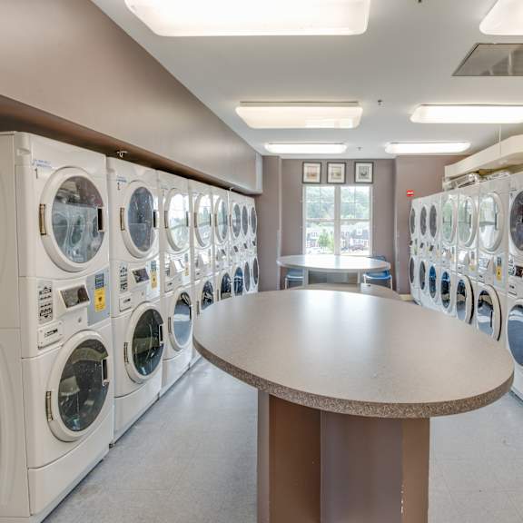 a laundromat with rows of washing machines and a round table in the middle.