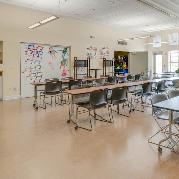 a classroom with tables and chairs and a whiteboard with drawings on it.