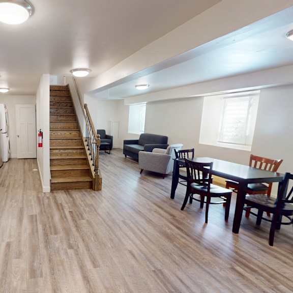 a kitchen with wooden floors and a staircase leading to a living room.
