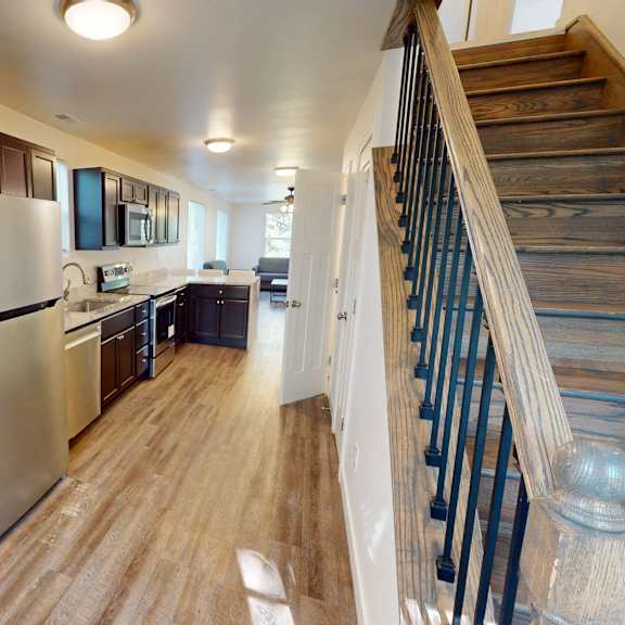 a kitchen with a stainless steel refrigerator and wooden stairs.