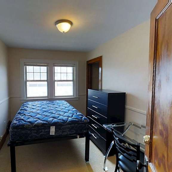 a bedroom with a bed, dresser, and television.