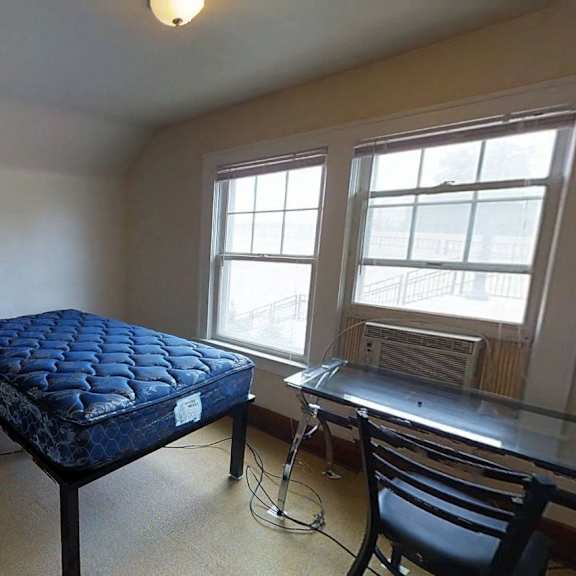 a room with a bed, chair, and window.