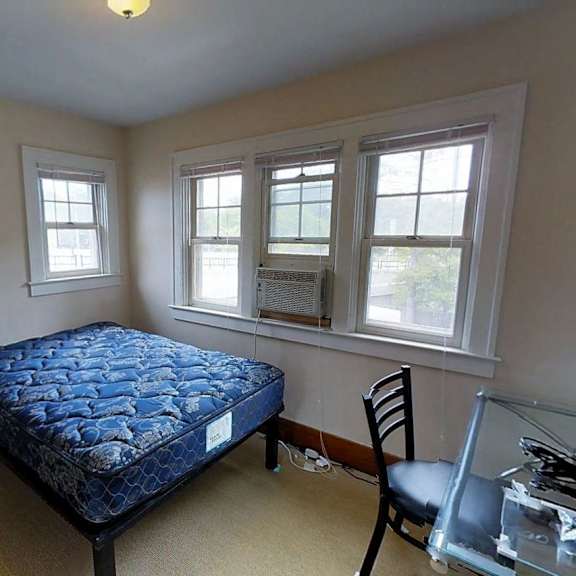 a bedroom with a bed, chair, and window.